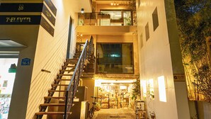Un edificio moderno con una escalera que conduce a un nivel superior. Se observan indicaciones de una tienda 7-Eleven y el número de habitación 16-5.