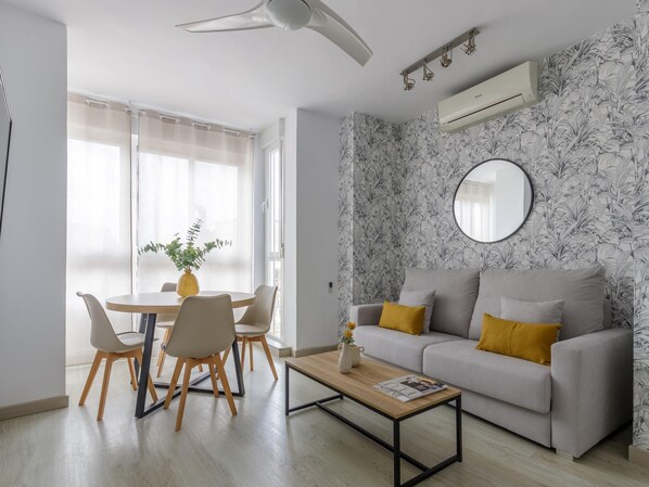 A modern living room with a sofa, coffee table, and dining area.