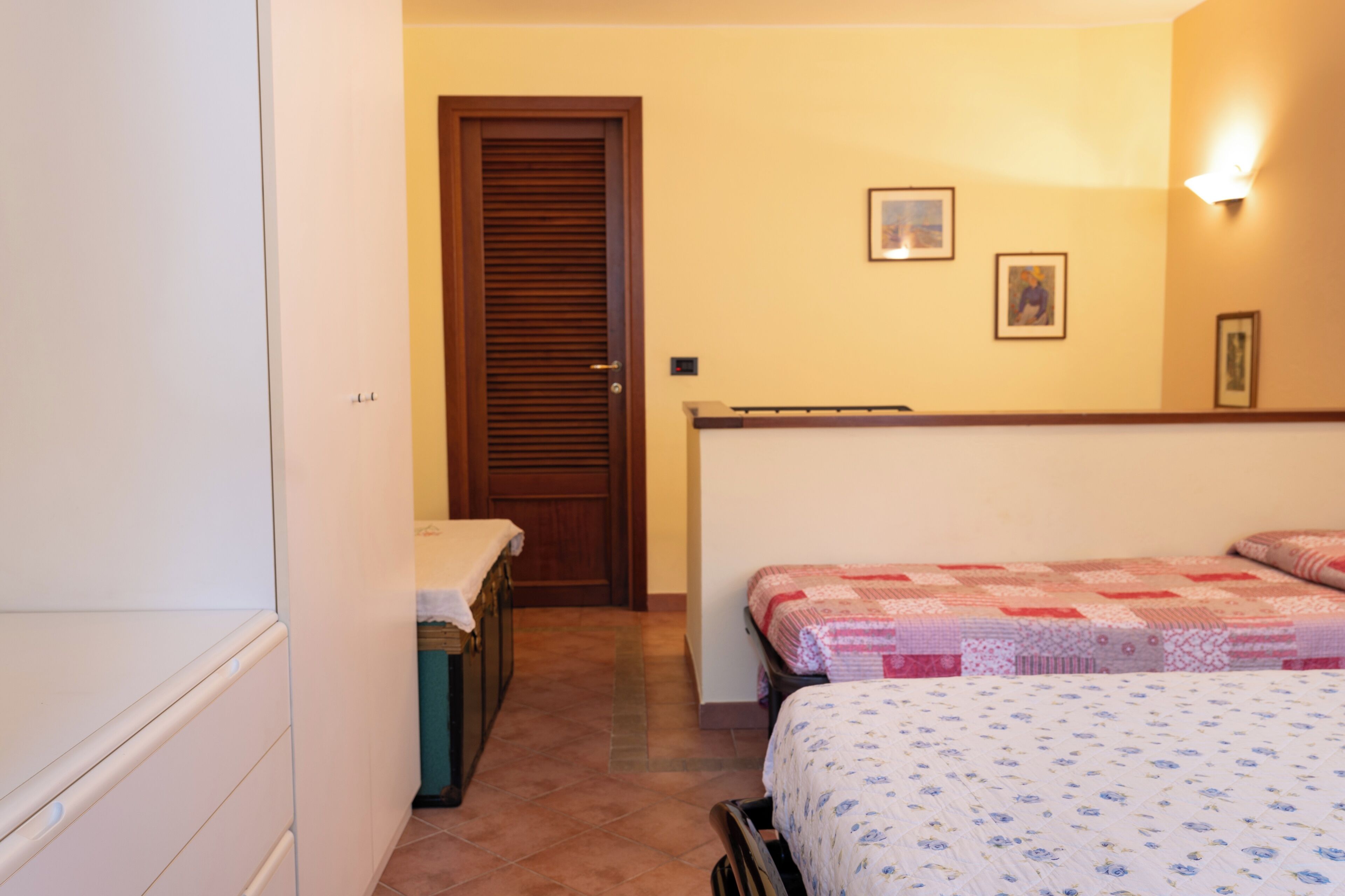 Een slaapkamer met twee bedden, een garderobe en een deur naar een andere kamer.