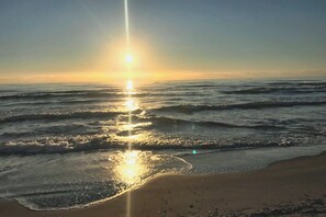 A beach with waves and sunlight reflecting on the water.