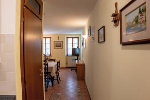 A hallway with a dining area, a television, and framed pictures on the wall. - Suite Carla cozy apartment in Petrasanta center (Pietrasanta)