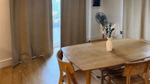 Ein Essbereich mit Tisch, Stühlen, einer Blumenvase, einer Deckenleuchte und einem Wandventilator.