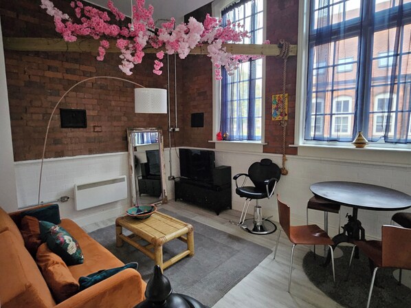 Relax in this inviting living space with a comfortable sofa, dining table, and brick accent wall.