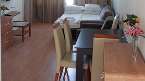A hotel room with a bed, a desk, a chair, a dresser, and a TV.