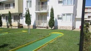 A grassy area with a green putting green and a yellow border.