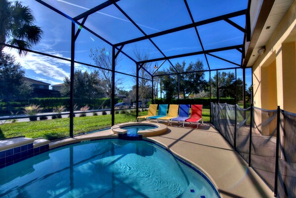 A covered outdoor swimming pool with a view of the surrounding landscape, including a grassy area and trees.