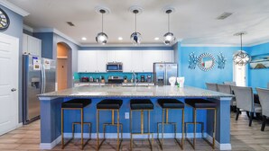 A kitchen with a central island, bar stools, and modern appliances.