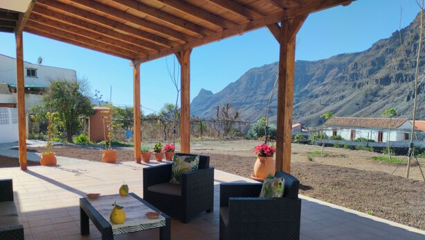 An outdoor patio with wicker furniture, potted plants, and a view of mountains. - La Casita Fataga Sleeps 4 with Garden (Fataga)