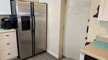 Eine Küche mit einem Edelstahl-Kühlschrank, einer Kaffeemaschine und einem Geschirrspüler.