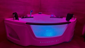 A modern, pink-lit jacuzzi with a digital interface, a built-in massage chair, and a control panel.