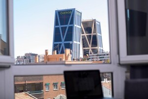 On aperçoit un bâtiment sur lequel on peut lire l’inscription « Bankia », vu à travers une fenêtre, avec un ordinateur portable posé sur un bureau.