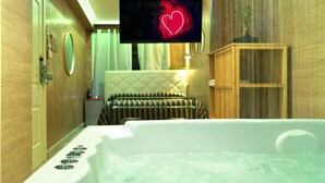 A modern bathroom with a bathtub, a television mounted on the wall, and a wooden cabinet. - HOTEL CABALLERO ERRANTE (Madrid)
