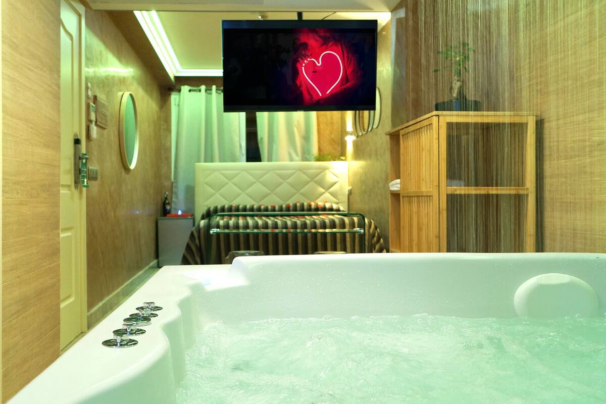 A modern bathroom with a bathtub, a television mounted on the wall, and a wooden cabinet.