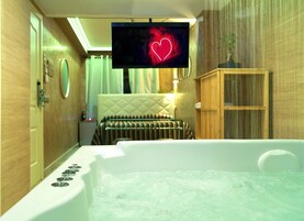 Un bagno moderno con una vasca, un televisore montato a parete e un armadietto in legno.