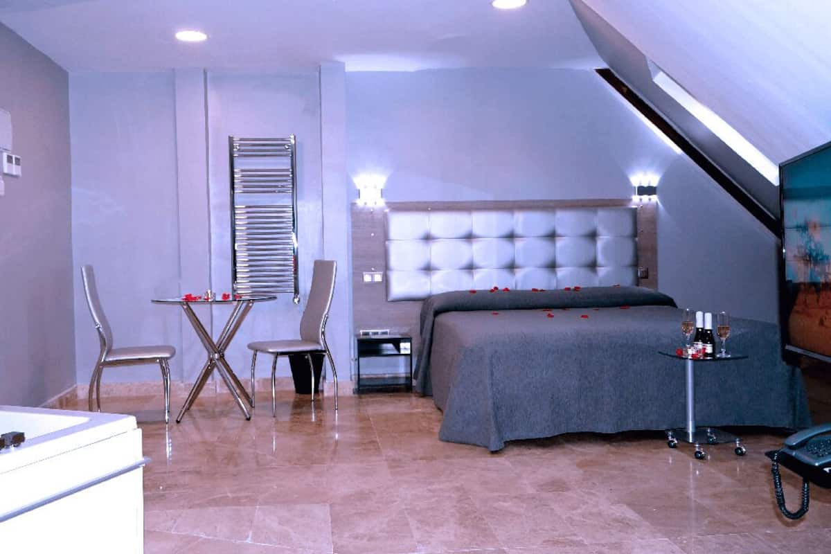 A modern bedroom with a large bed, a desk, and a chair.