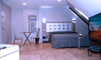 A modern bedroom with a large bed, a desk, and a chair.