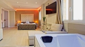 A modern hotel room with a large bed, a glass coffee table, a sofa, and a jacuzzi tub. - HOTEL CABALLERO ERRANTE (Madrid)