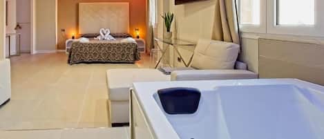 Una habitación de hotel moderna con una cama grande, una mesa de centro de cristal, un sofá y una bañera de hidromasaje.