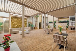 Un'ampia zona patio con pavimento in legno, un divano bianco, un tavolo da pranzo con sedie e piante in vaso.