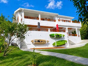 Un edificio de dos pisos con fachada blanca, un balcón en el nivel superior y una escalera que lleva a la entrada.