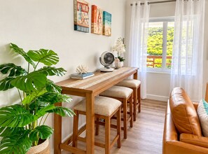 Una habitación con una mesa de comedor de madera, sillas, un sofá, una planta en maceta y obras de arte en la pared.