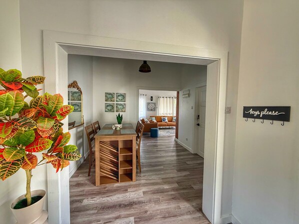 A hallway with a dining area, a sofa, and a sign that reads "keys please".