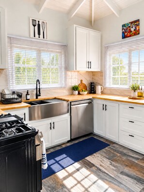 Una cocina moderna con armarios blancos, electrodomésticos de acero inoxidable y encimera de madera.