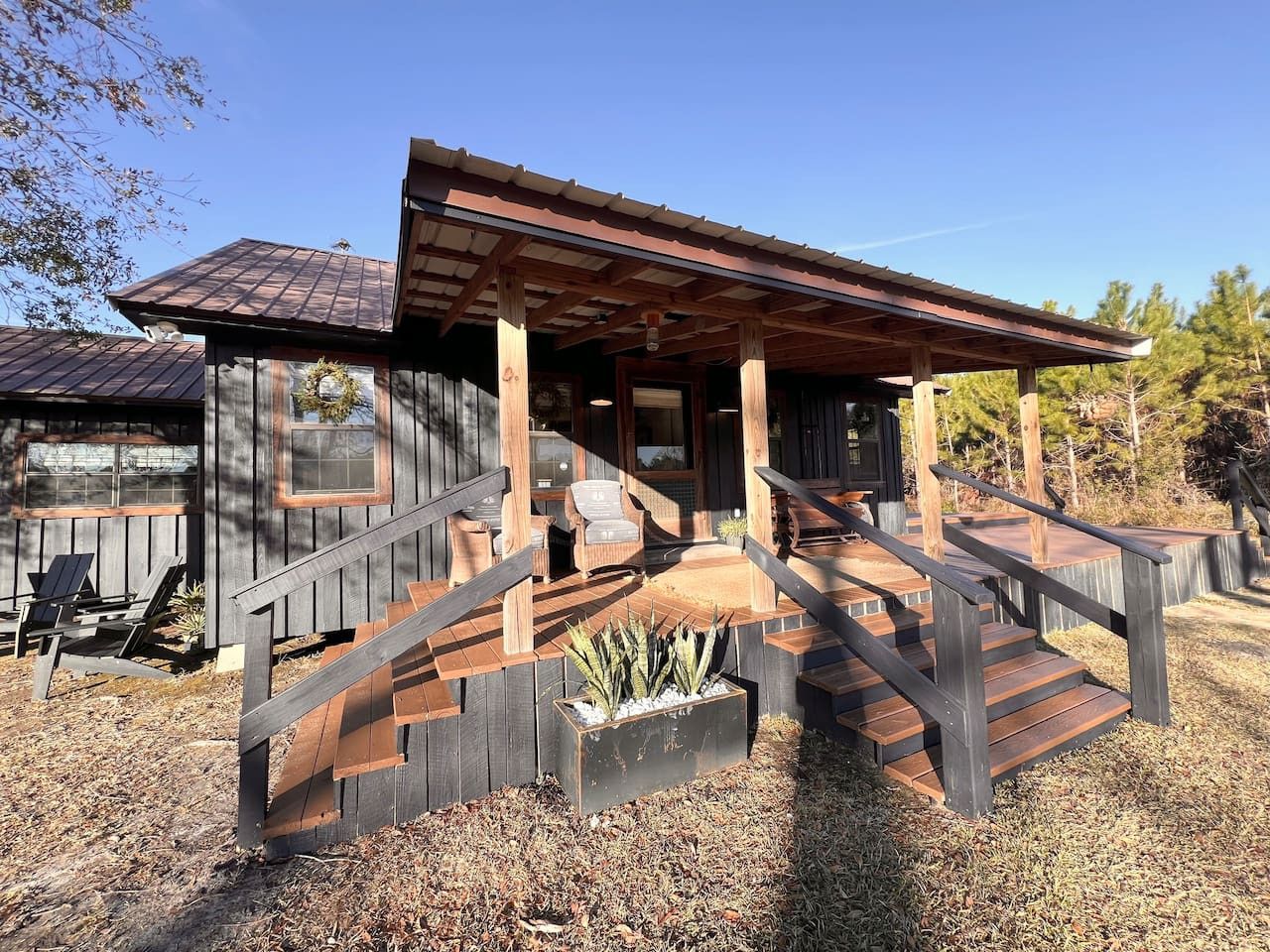 A wooden cabin with a porch, outdoor seating, and a staircase leading to the entrance.