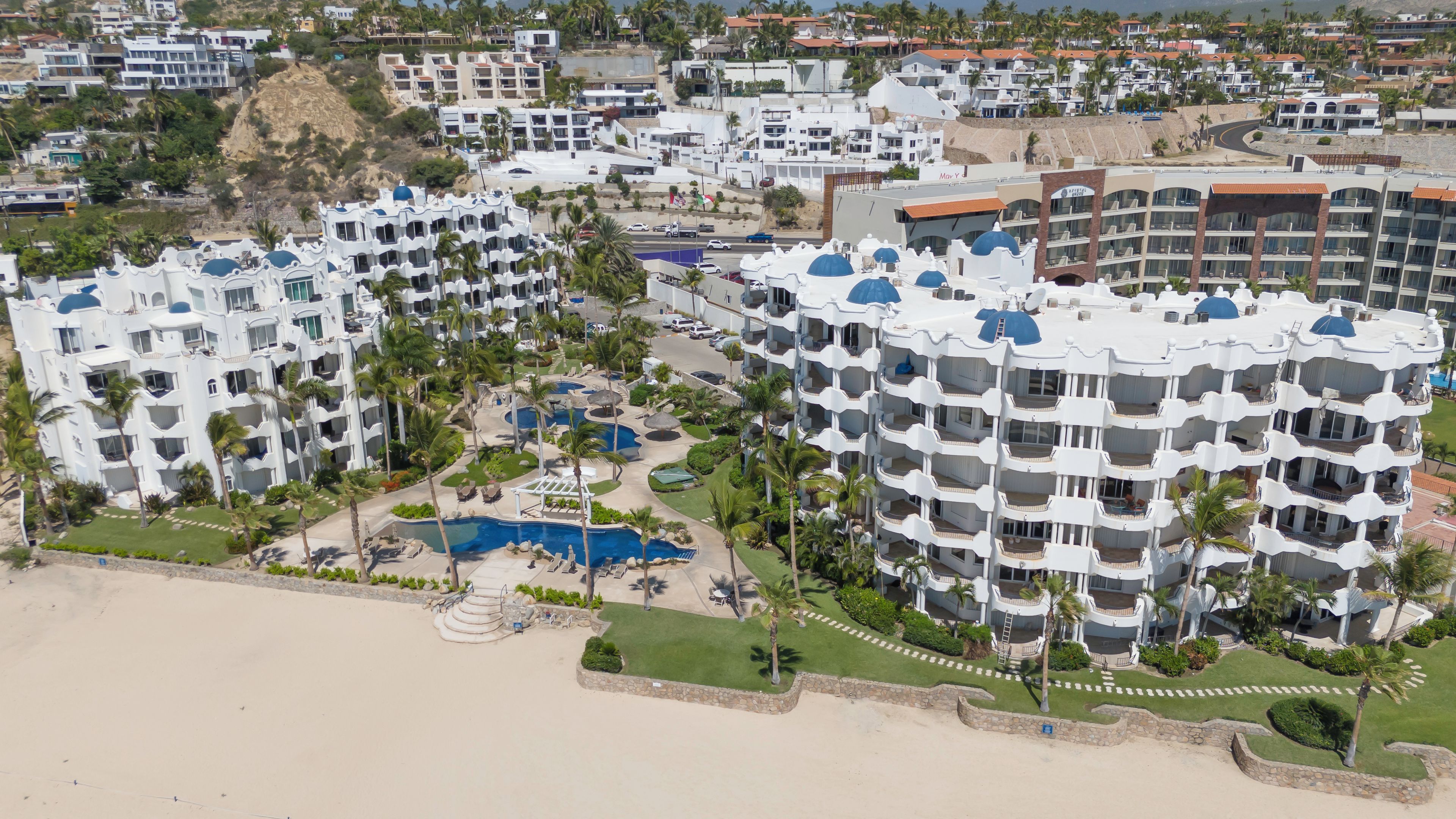A resort with multiple buildings, a swimming pool, and a beach area.