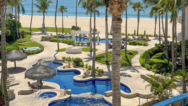 A resort with a pool area, palm trees, and a beach view. - Beachfront Escape at Mykonos Bay Resort 401B (San José del Cabo)