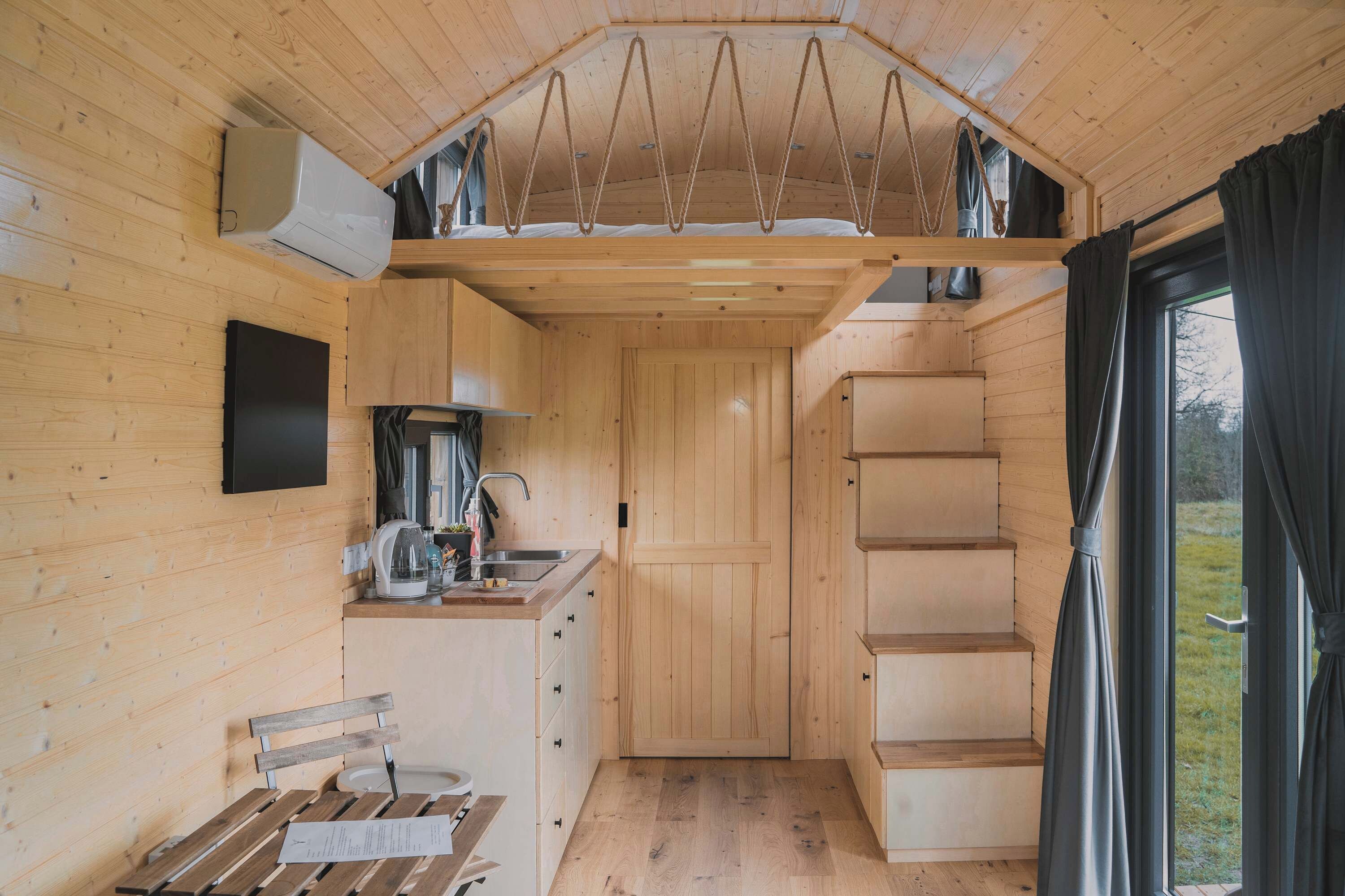 A compact kitchen with wooden cabinets, a sink, and a window with curtains.