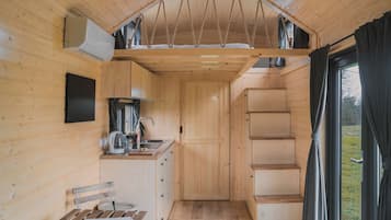 A compact kitchen with wooden cabinets, a sink, and a window with curtains.