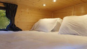 Una camera in legno con un letto, tende e una finestra.