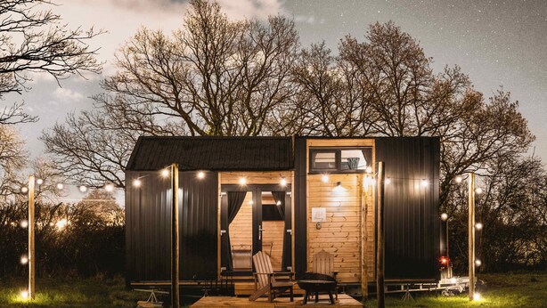 A small wooden cabin with a porch, a bench, and a table.