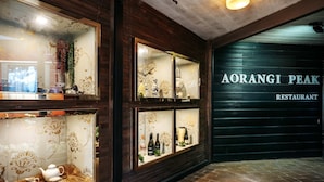 Interior de restaurante con paneles de madera y vitrinas de vidrio que exhiben vajillas y botellas.