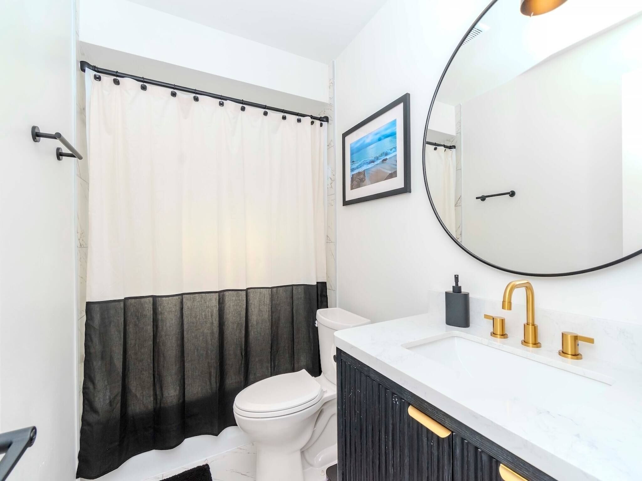 Un baño con inodoro, lavabo con detalles dorados, un espejo grande y cortina de ducha.