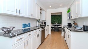 Une cuisine moderne avec des meubles blancs, un plan de travail noir et un plancher en bois.