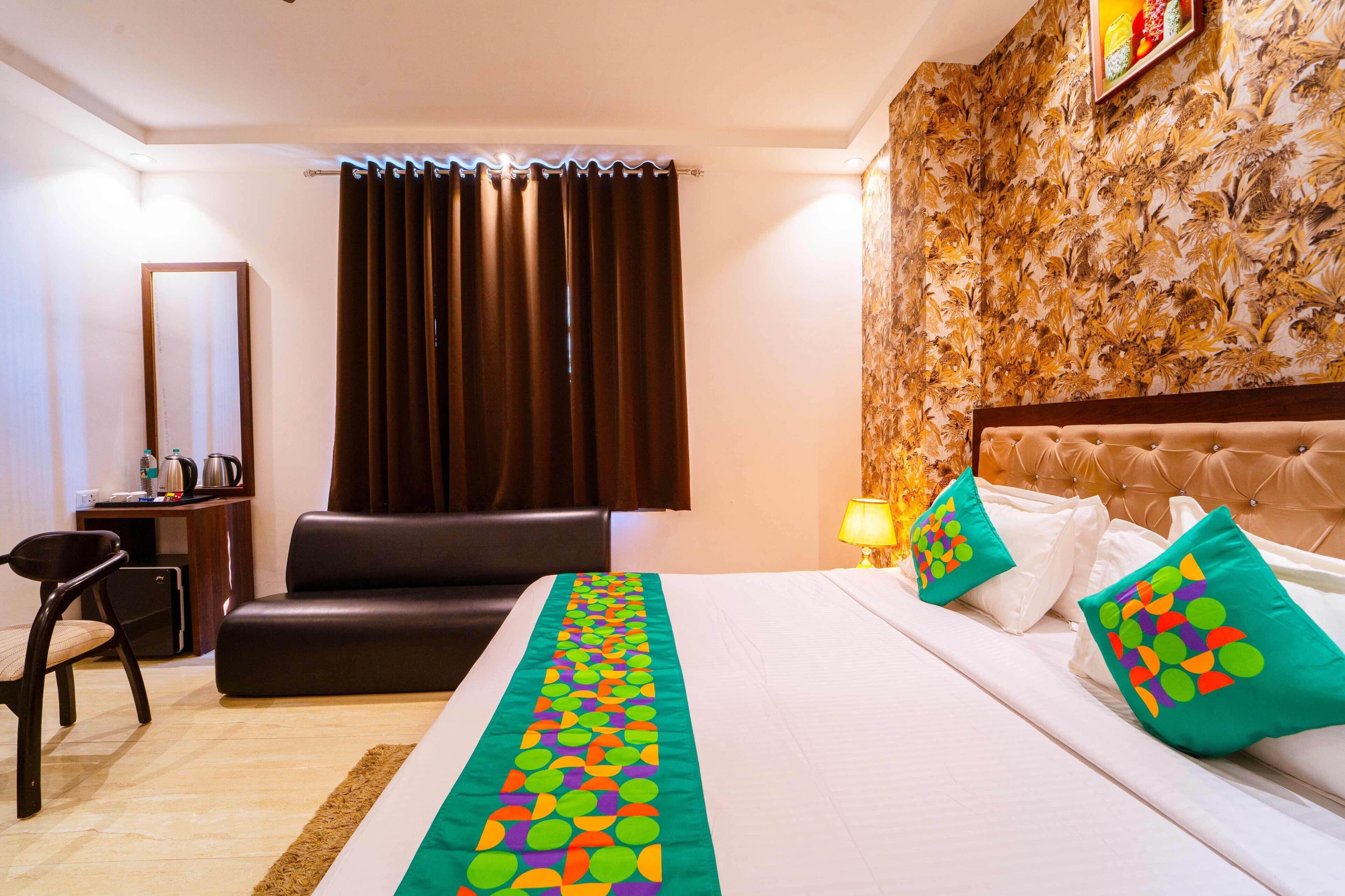 A hotel room with a bed, a sofa, a desk, and a mirror.