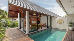 A modern house with a pool, wooden deck, and a dining area with outdoor furniture. - Unagi Mas Villas by Emana (Mas)