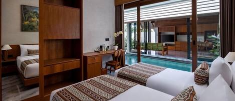 A hotel room with two beds, a desk, and a view of a pool.