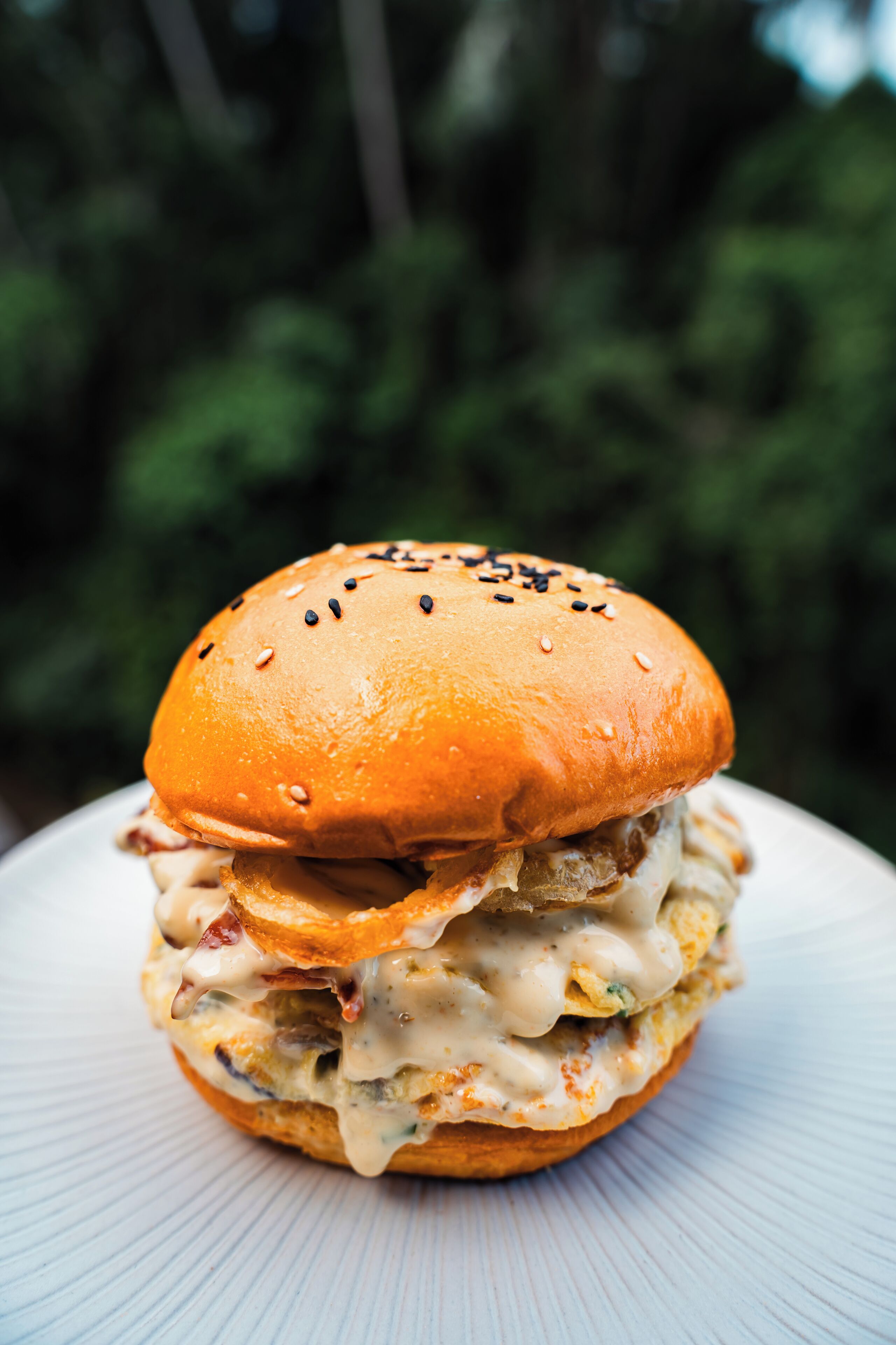 Een hamburger met een sesamzaadbolletje op een wit bord.