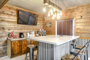 Eine Bar mit Holzvertäfelung, einem flachbildfernseher an der Wand und einem Schild mit der Aufschrift 'Welcome to the Bar'.