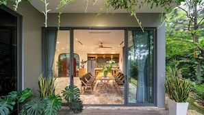 Una casa moderna con una porta in vetro che conduce a una zona pranzo con tavolo e sedie.
