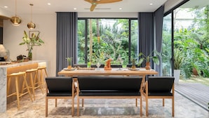 Zona pranzo moderna con tavolo in legno, panche nere imbottite e ventilatore a soffitto.