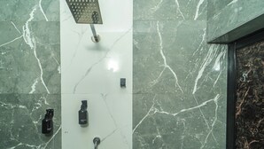A bathroom with a shower, a handheld showerhead, a handheld body wash, and a handheld shampoo bottle. - Artham Guesthouse (Morjim)