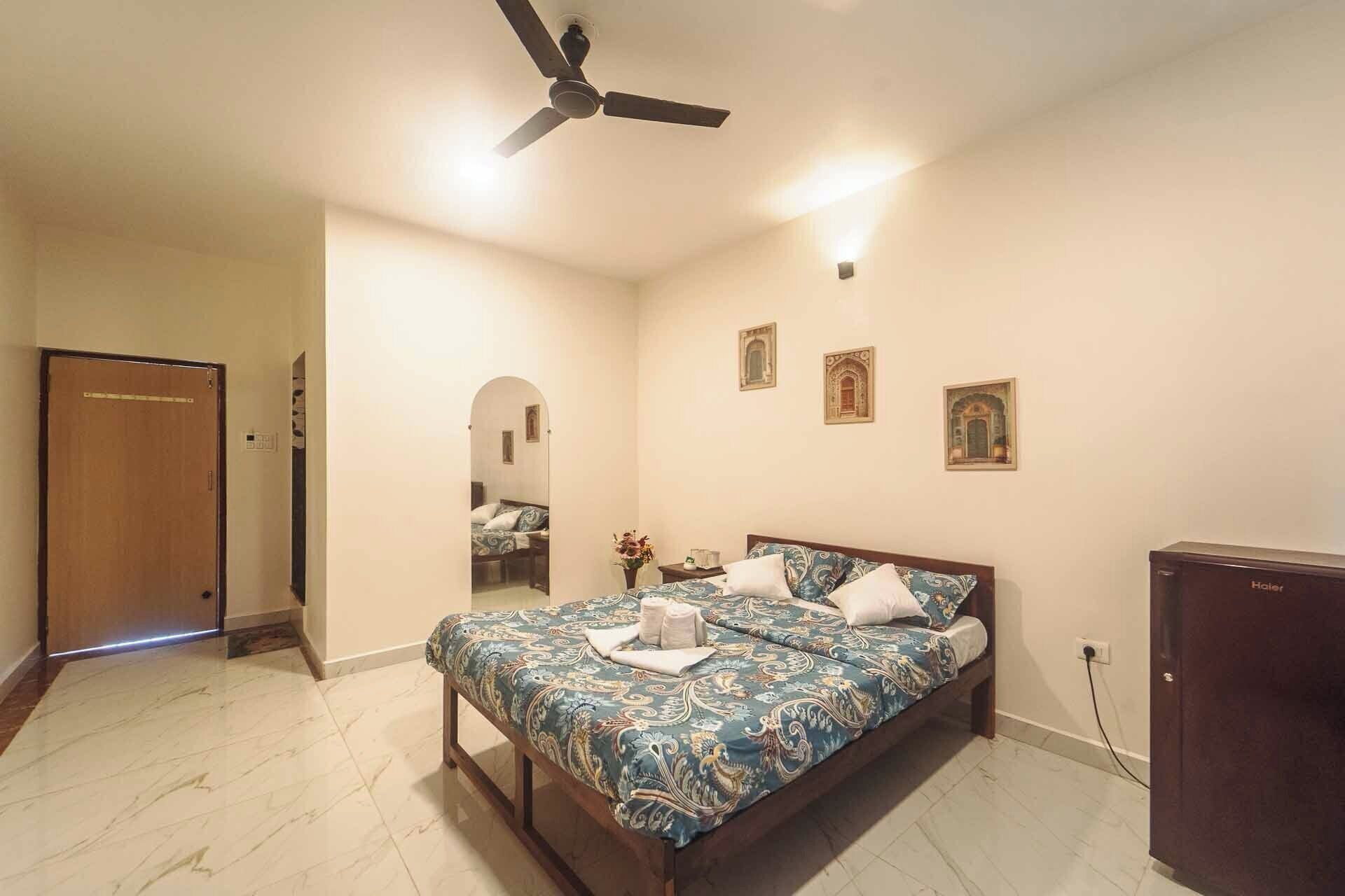 A bedroom with a bed, a ceiling fan, a nightstand, and a mirror.