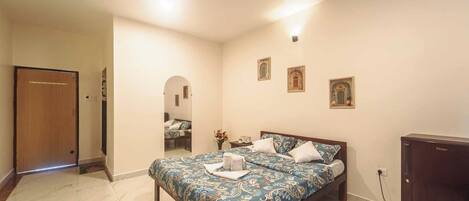 A bedroom with a bed, a ceiling fan, a nightstand, and a mirror.