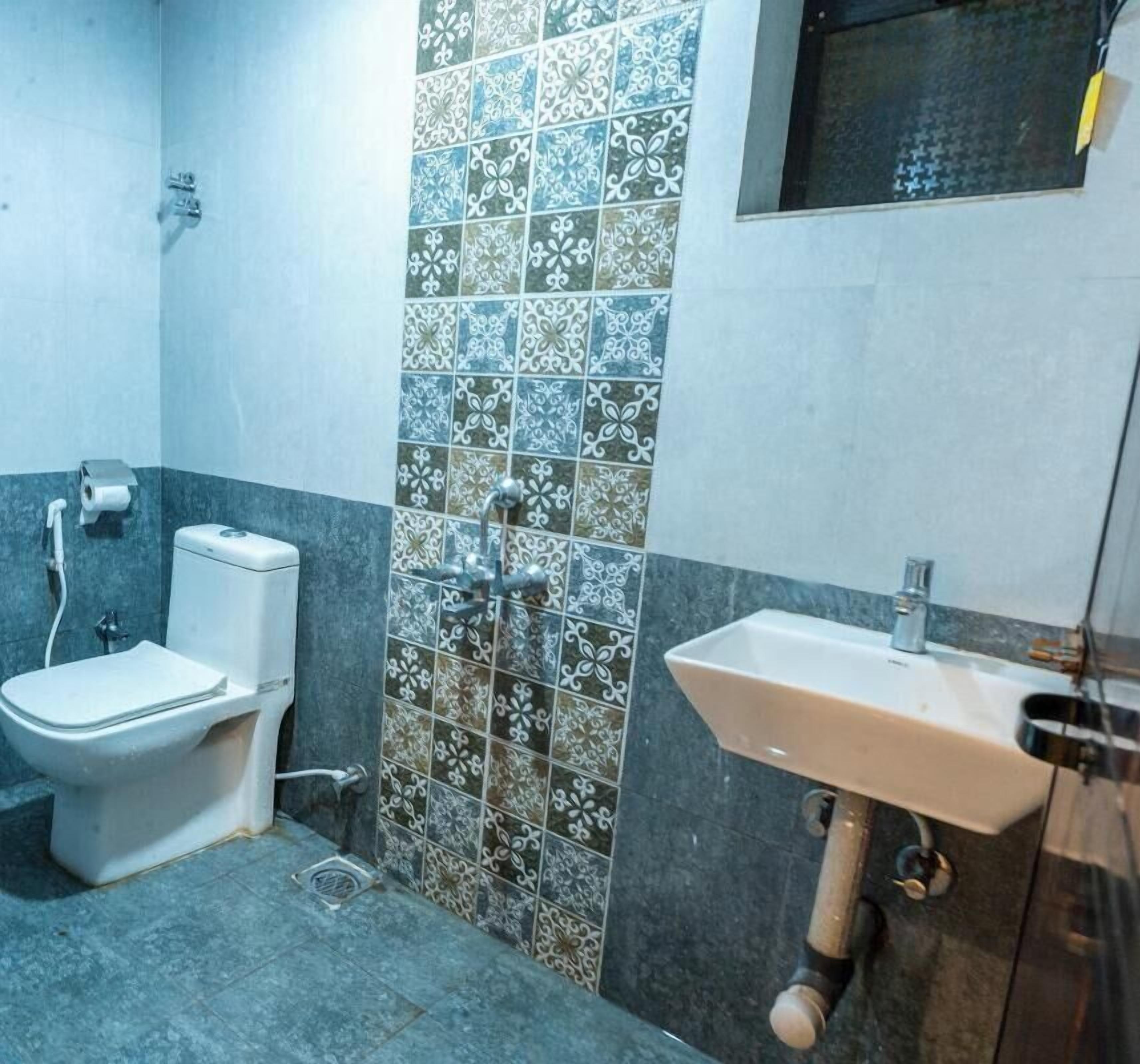 A bathroom with a toilet, sink, and decorative tiled wall.