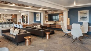 A spacious living area with a modern sofa set, a dining table, and a kitchen area with a large TV.
