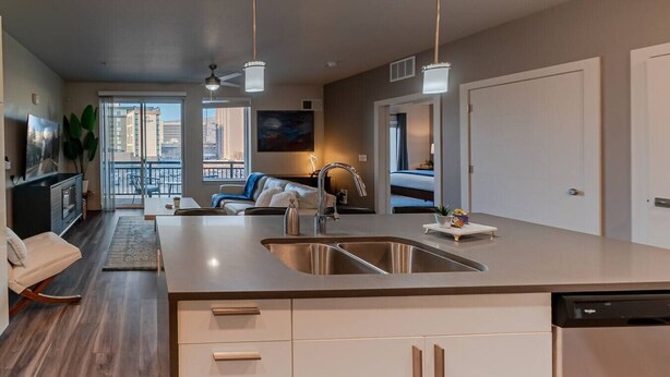 A modern kitchen with a central island, built-in cabinets, and a large window overlooking the city.